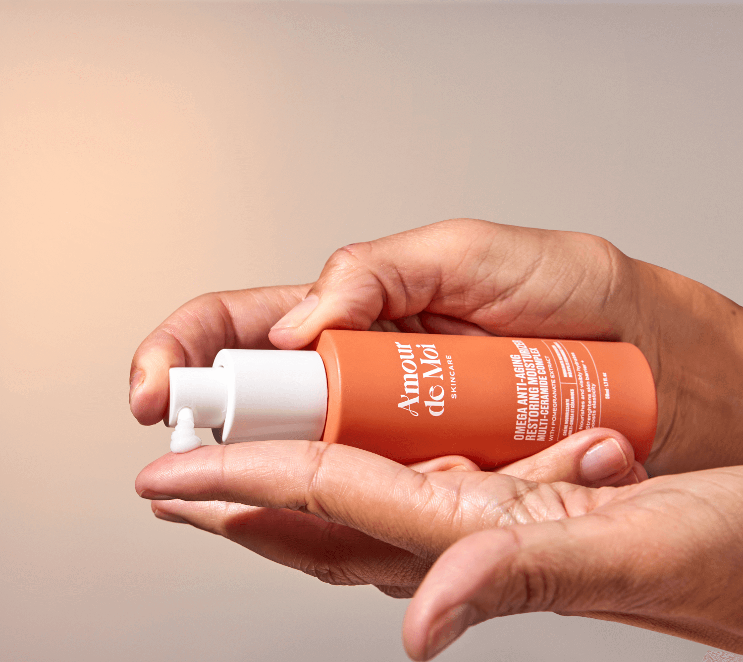 Person holding a bottle of anti-aging multi ceramide omega skin restoring moisturizer with a blurred background