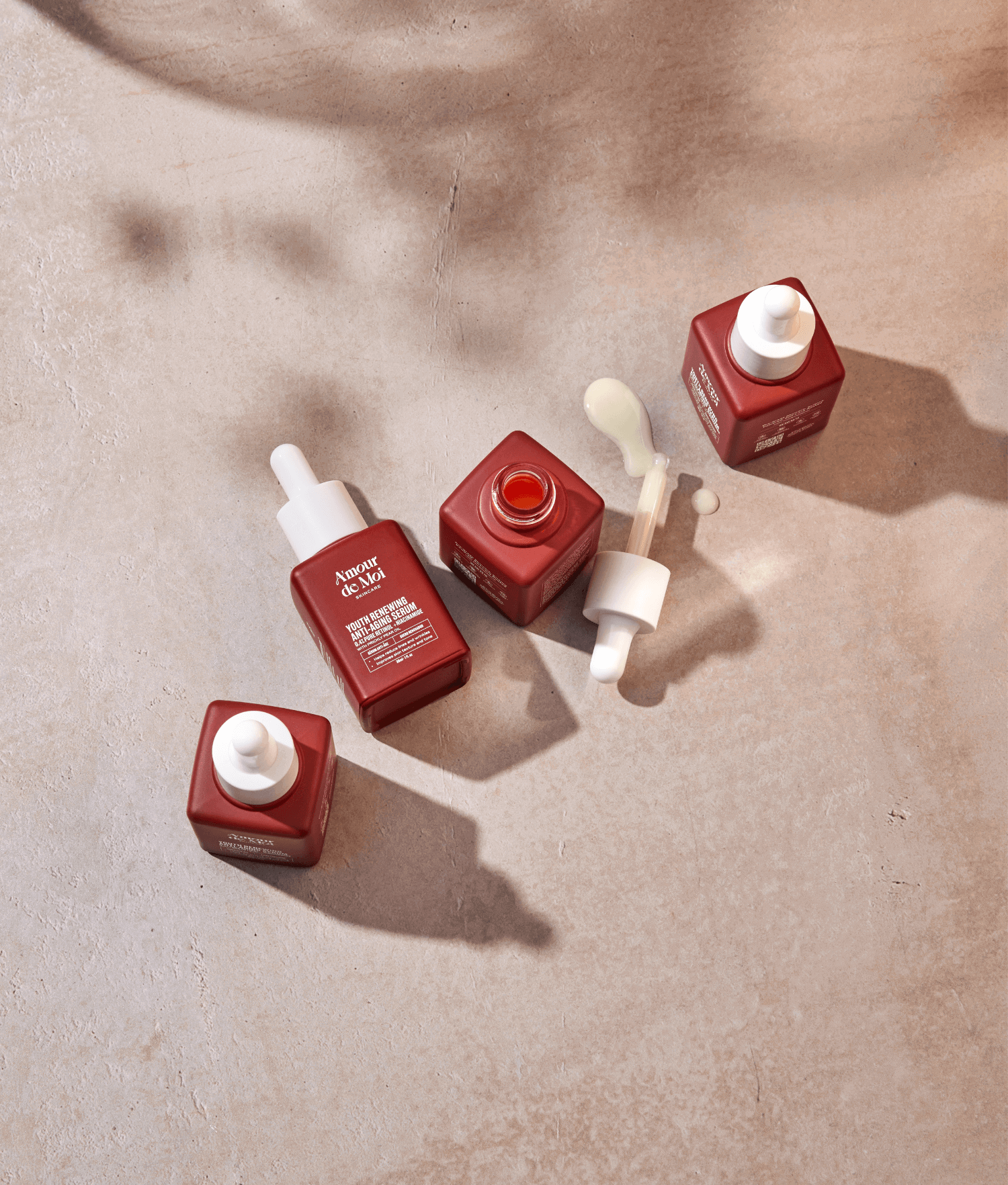 four bottles of anti-aging retinol niacinamide youth preserving serum sitting on a beige counter with shadows