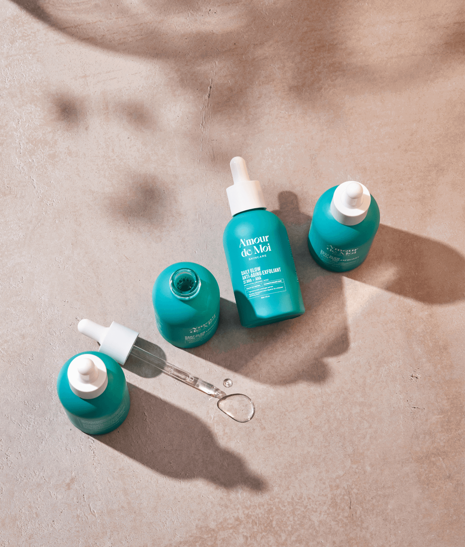 four bottles of 2% BHA + AHA Daily Glow Exfoliant sitting on a beige counter with shadows