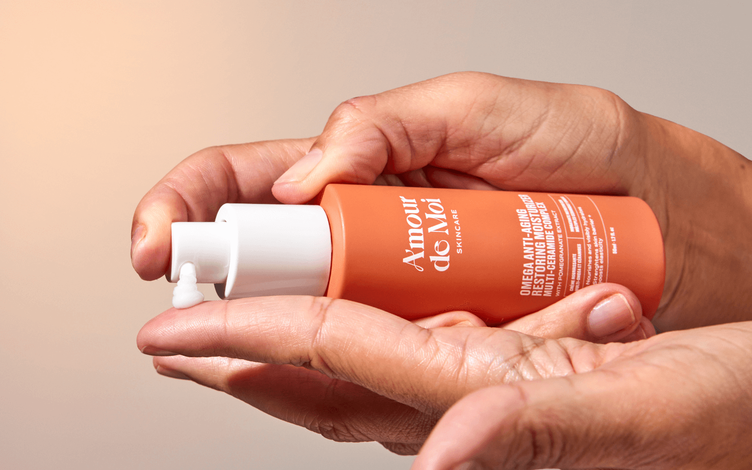 Hand holding a bottle of Amour de Moi's skin moisturizer with a blurred background