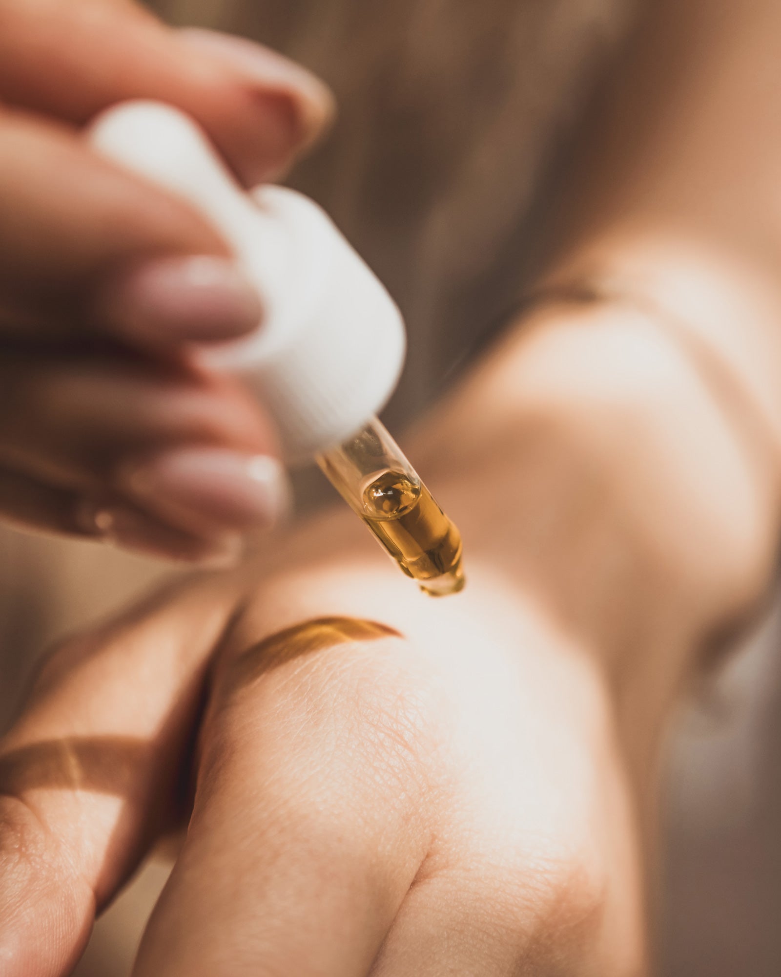 A woman dropping Amour de Moi Skincare youth preserving serum to her hand with a dropper