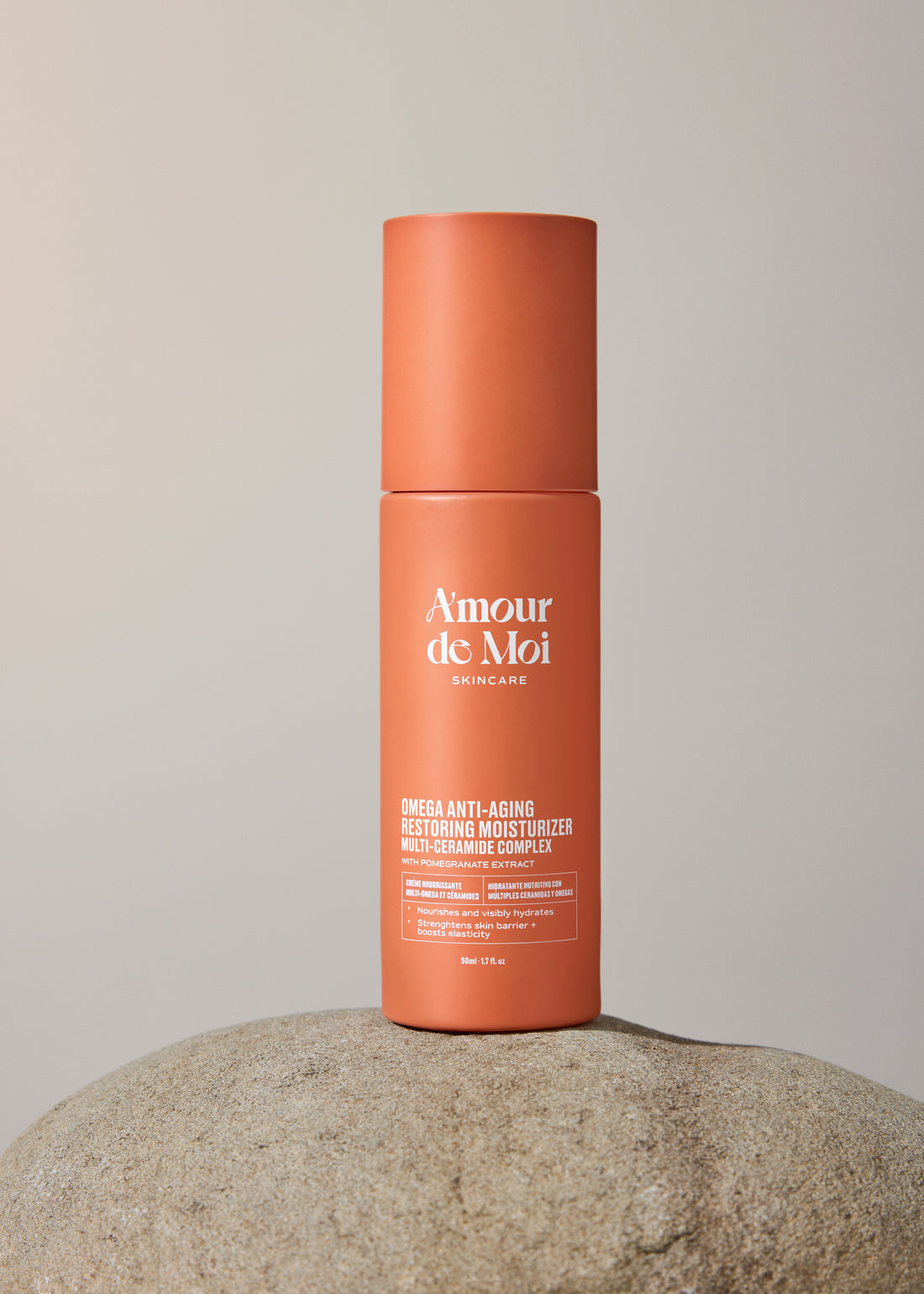 A bottle of multi-ceramide complex omega anti-aging restoring moisturizer sitting on a rock