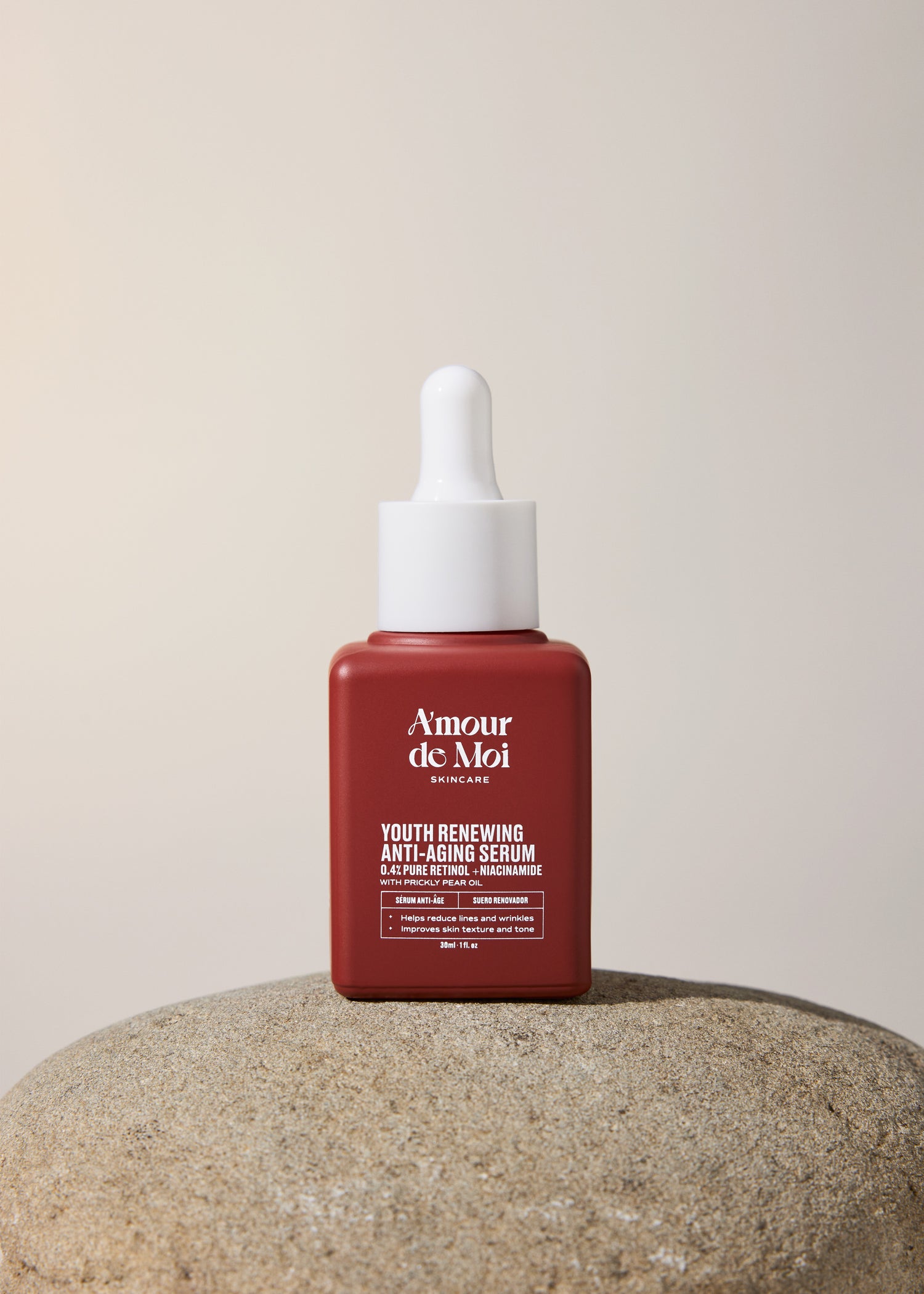 A bottle of youth renewing anti-aging serum sittinng on a rock