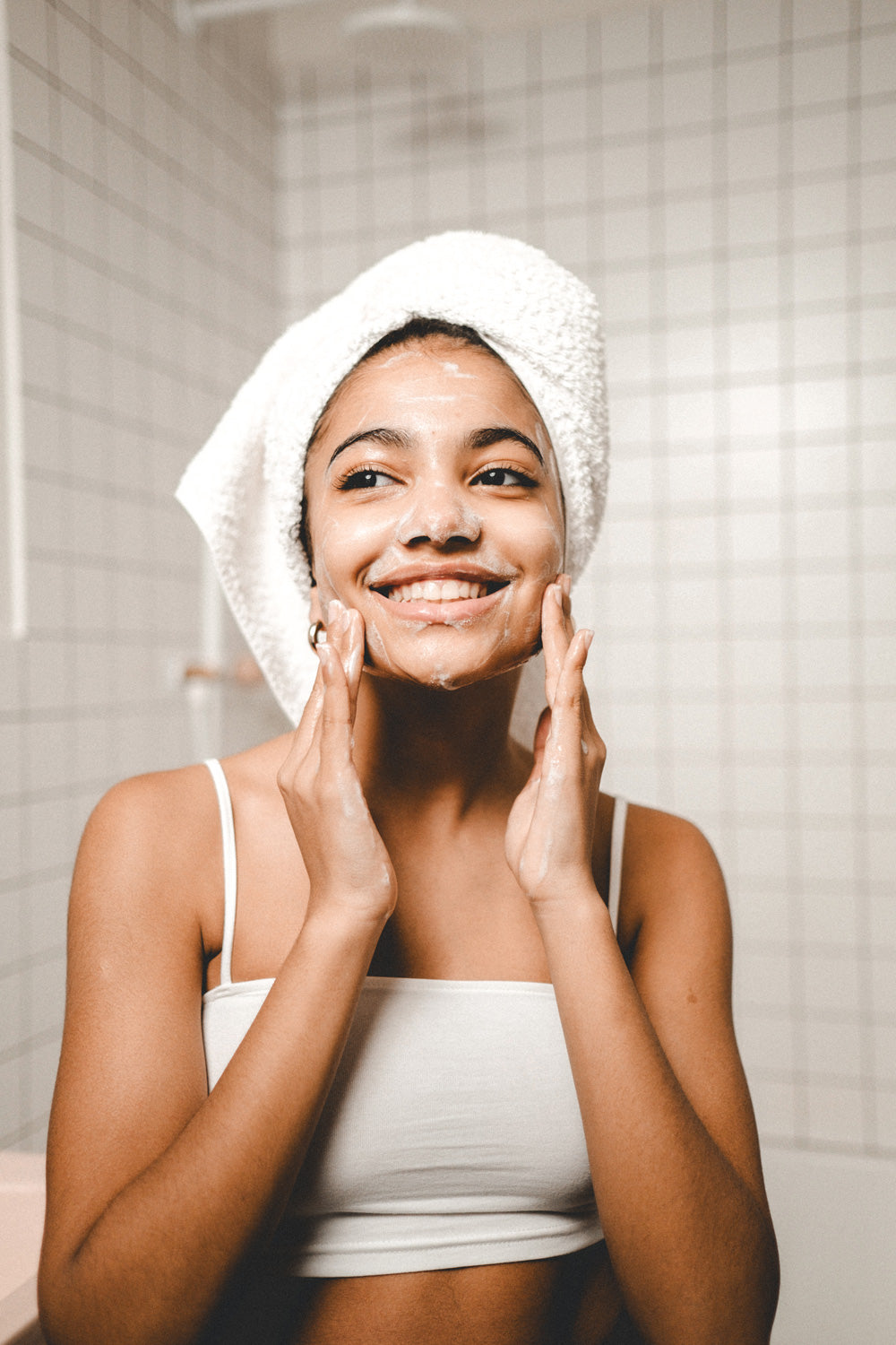 Woman putting natural anti-aging cream on her face in bathroom