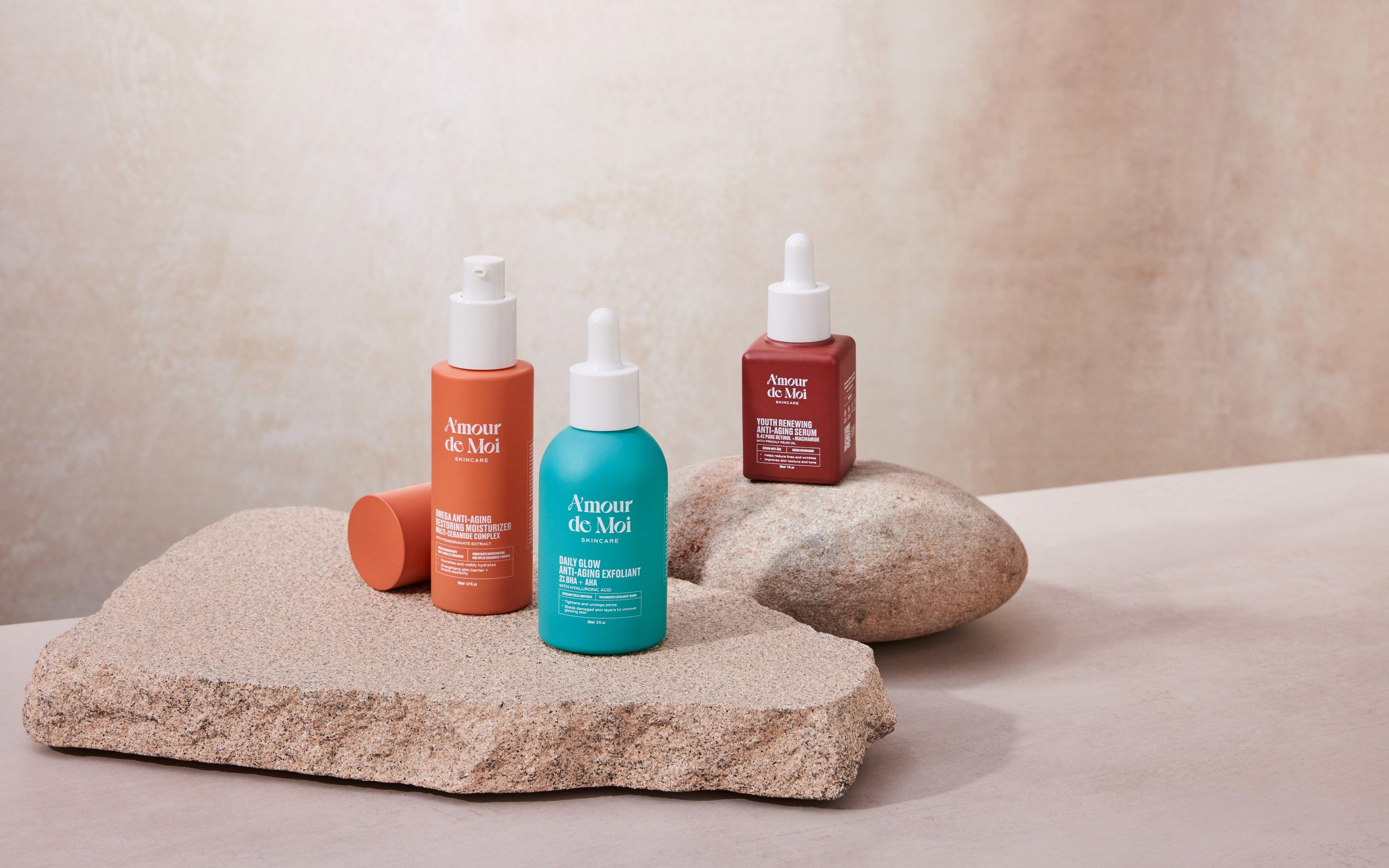 All three amour de moi anti-aging skincare products laying on rocks being showcase